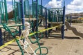 Adult skeleton sitting on playground equipment at an empty closed park on a nice day