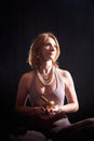 An adult skinny blonde woman doing yoga exercises on a black background in the studio. Sporty girl model posing in a Royalty Free Stock Photo