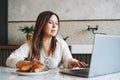 Adult smiling brunette woman having breakfast with opened laptop in kitchen at the home Royalty Free Stock Photo