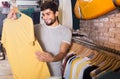 adult smiling male buyer choosing t-shirt in the dress shop