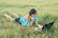 Adult smiling woman with glasses using computer laptop on grass. Female blogger, freelancer working in nature Royalty Free Stock Photo