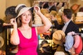 adult smiling woman try on boater hat in shopping mall Royalty Free Stock Photo