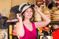 adult smiling woman try on boater hat in shopping mall Royalty Free Stock Photo