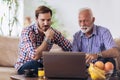 Adult Son Helping Senior Father With Computer