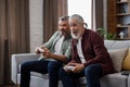 Adult son and senior father having fun, enjoy spending time together. Two generations family playing video games using Royalty Free Stock Photo