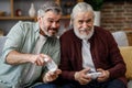 Adult son and senior father having fun, enjoy spending time together. Two generations family playing video games using Royalty Free Stock Photo