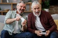 Adult son and senior father having fun, enjoy spending time together. Two generations family playing video games using Royalty Free Stock Photo