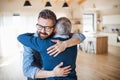 An adult son and senior father indoors at home, hugging. Royalty Free Stock Photo