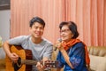 Adult son and senior mom sing a song while relaxed sitting on couch