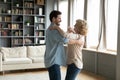 Adult son and senior mum dancing waltz in living room