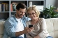 Adult son showing to older mother new application on smartphone