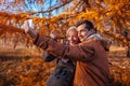 Adult son taking selfie with his mother using smartphone in autumn park. Family time Royalty Free Stock Photo