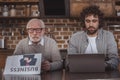 adult son using laptop and senior father reading business newspaper Royalty Free Stock Photo