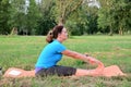 An adult sportive woman is engaged in stretching outdoors in the park