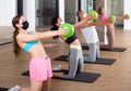 Adult sports people in protective masks performs an exercise, holding a mini Pilates ball in front of them Royalty Free Stock Photo