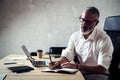 Adult stylish businessman wearing a classic glasses and working at the wood table in modern loft studio.Bearded middle Royalty Free Stock Photo