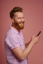 Adult stylish handsome redhead bearded smiling man holding phone