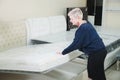 An adult stylish woman with a short-cut blonde chooses a large orthopedic bed with a lifting mattress in a furniture Royalty Free Stock Photo