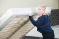An adult stylish woman with a short-cut blonde chooses a large orthopedic bed with a lifting mattress in a furniture Royalty Free Stock Photo