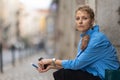 Adult stylish woman with short hair sitting on the european street and holding an electronic cigarette - looking in the Royalty Free Stock Photo