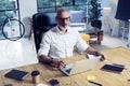 Adult successful businessman wearing a classic glasses and working at the wood table in modern coworking studio.Stylish Royalty Free Stock Photo