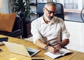 Adult successful businessman wearing a classic glasses and working at the wood table in modern coworking studio.Stylish Royalty Free Stock Photo