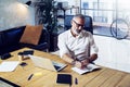 Adult successful businessman wearing a classic glasses and working at the wood table in modern coworking studio.Stylish Royalty Free Stock Photo