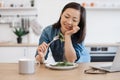 Adult tasting vegan meal at kitchen table near computer