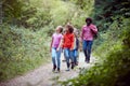 Adult Team Leaders With Group Of Children At Outdoor Activity Camp Walking Through Woodland