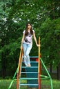 Adult or teenager girl having fun on children playground. Urban teen girl with brunette long hair posing on playground park. Royalty Free Stock Photo