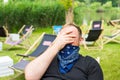 Adult tired and upset man in bandana as a face mask in a city cafe terrace.