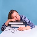 Adult tired woman sleeping on books while studying, blue background Royalty Free Stock Photo