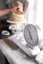 An adult tortilla maker is weighing a stack of tortillas using an analog scale Royalty Free Stock Photo