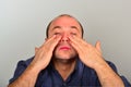 An adult and unshaven man in a blue shirt applies a mask of cream on his face, the concept of fashion, style and personal care