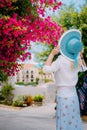 Adult woman with blue hat enjoy vivid flowers in cute Assos town at Kefalonia island. Amazing summer time on Royalty Free Stock Photo