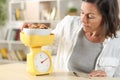 Adult woman dieting measuring food with scale at home Royalty Free Stock Photo