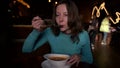 Adult woman is dining alone in small cafe, eating hot soup