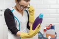 Adult woman doing cleaning with detergents. Woman in glasses, professional uniform in bathroom, toilets room, reading instructions
