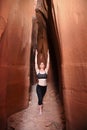 Woman practicing exalted warrior yoga pose in red rock slot canyon