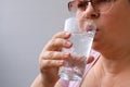 Adult woman drinking clear water from a glass, thirst concept, healthy refreshing drinks, diet, weight loss