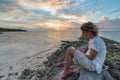 Adult woman with eyeglasses reading ebook relaxing at tropical beach dramatic sky holidays vacation concept