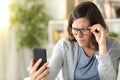 Adult woman with eyesight problems reading phone at home Royalty Free Stock Photo