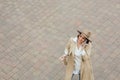 Adult woman in hat and coat talking on cell phone standing on brick stone floor