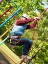 Adult woman in a helmet and with a safety system climbs a rope ladder Royalty Free Stock Photo