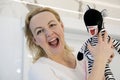 an adult woman in her hands with a toy zebra soft toy striped with real teeth false teeth woman laughs parodying a toy