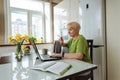 Adult woman housewife uses laptop to do home accounting and pay bills Royalty Free Stock Photo