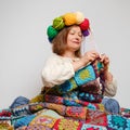 An adult woman knits a plaid crochet with balls of yarn on her head
