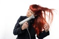 An adult woman, lady, with long red hair, dries her hair with a hairdryer. on white background. Hair care Royalty Free Stock Photo