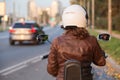 An adult woman motorcyclist on her bike is in the city, rear view