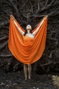 Adult woman in orange dress, dancing under tree roots Royalty Free Stock Photo